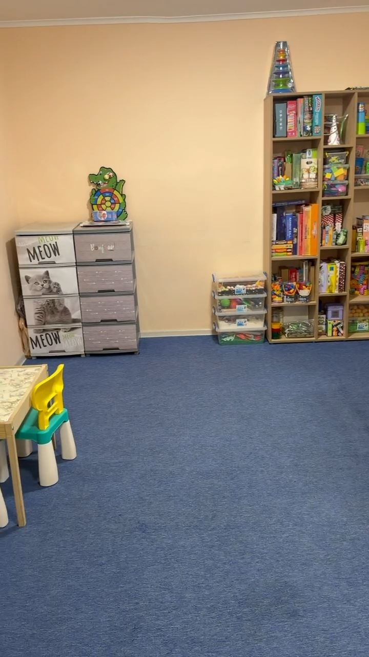 Кімната для малюків: полиці з іграми та книжками, маленькі столики
